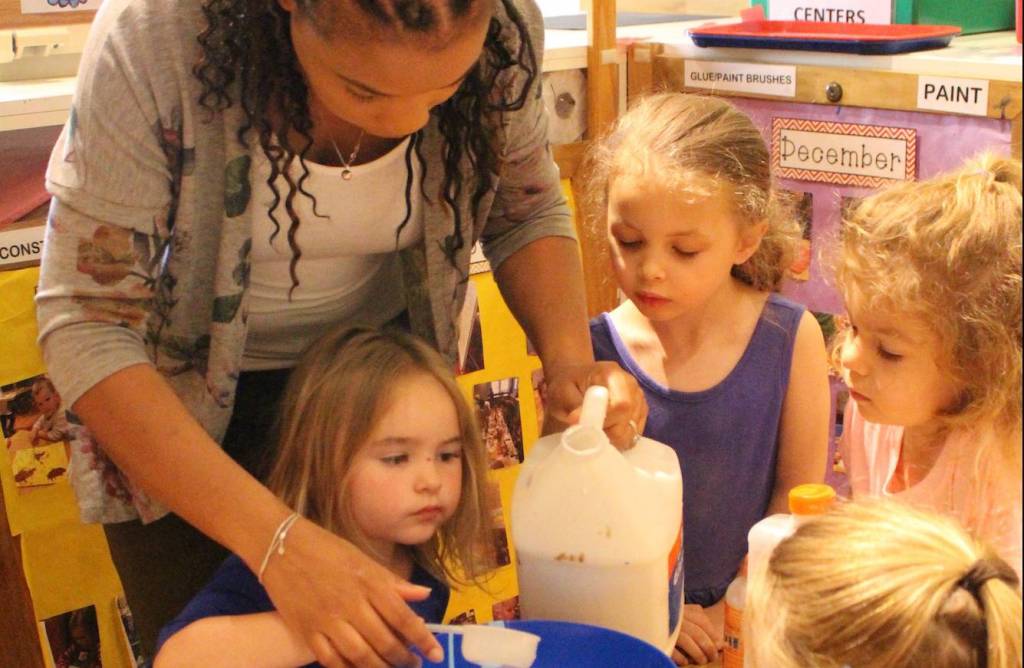 Teacher helping young female students with art project